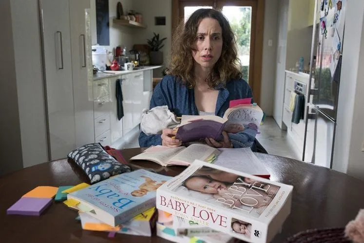 Alison Bell como audrey em Turma do Peito, rodeada de livros e bagunça