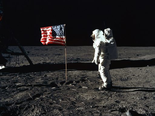 Homem de traje espacial na lua em frente à bandeira dos Estados Unidos da América