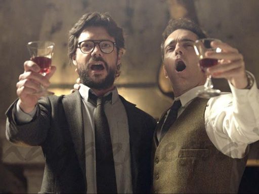 Professor e Berlin levantando taças de vinho cantando