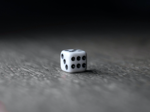 "Pequeno dado branco colocados sobre mesa de madeira”